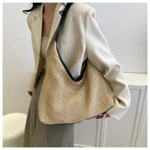 Detail of woven straw hobo bag with black PU leather trim on a model shoulder