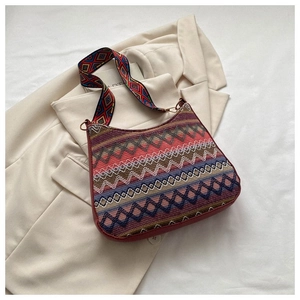 Detail of bohemian ethnic woven crossbody bag with colorful patterns and wide shoulder strap