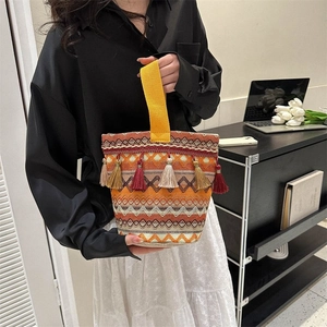Dettaglio della borsa tessuta in stile bohémien con nappe colorate e tracolla gialla vivace