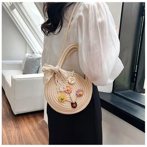 Détail d'un sac en paille tressée avec fleurs tricotées et nœud en dentelle sur mannequin
