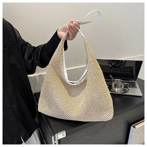 Detail of hand-woven straw hobo tote bag with a white leather handle for office use