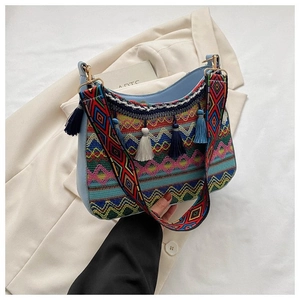Detail of ethnic woven bag with colorful patterns, fringe tassels and wide embroidery strap