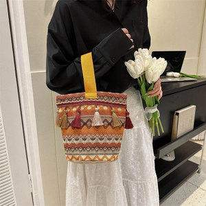 Dettaglio della borsa etnica intrecciata con nappe colorate e motivi geometrici a onde