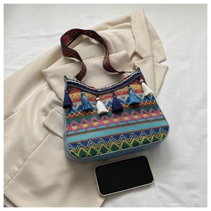Detail of bohemian woven bag with ethnic patterns, tassel charms and wide jacquard strap