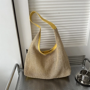Detail of beige woven hobo bag featuring vibrant yellow PU leather strap and trim finish