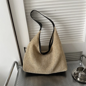 Detail of hand-woven beige hobo tote bag with black faux leather strap and large capacity