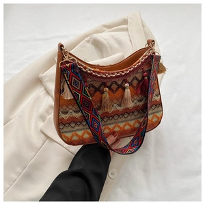 Detail of ethnic woven bag with colorful tassels and wide patterned shoulder strap