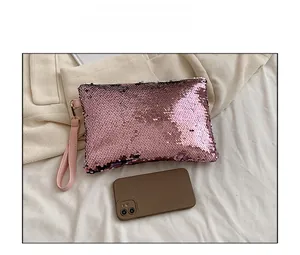 Pink sequin evening clutch bag shown next to a smartphone for size reference