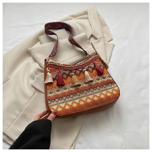 Detail of bohemian geometric woven bag featuring colorful tassels and wide jacquard strap