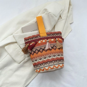 Dettaglio della borsa a secchiello etnica in maglia con motivi geometrici e nappe colorate