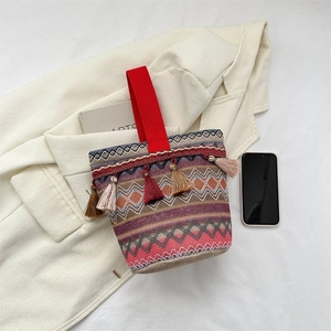 Borsa a secchiello ricamata etnica con nappe e manico rosso su blazer beige