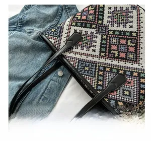 Detailed close-up of colorful geometric woven tote bag with slim black leather handles