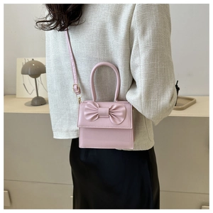 Detail showing pink PU leather crossbody bag with bow decoration worn by model