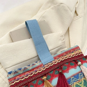 Dettaglio borsa etnica ricamata con nappe colorate e trame intrecciate in stile boho