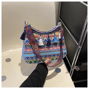 Detail of bohemian embroidery bag with geometric patterns, blue tassels and wide strap