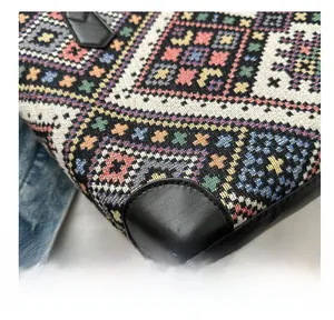 Detail of colorful woven tote bag with reinforced black leather corners and stitching