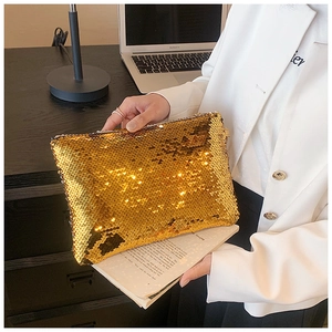 Detail of gold sequin evening clutch bag held by a model with metallic reflective surface
