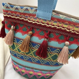 Dettaglio macro della borsa intrecciata multicolore con nappe vivaci e motivi geometrici