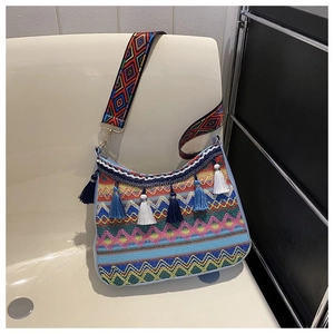 Macro detail of Bohemian woven shoulder bag with colorful tassels and wide ethnic strap