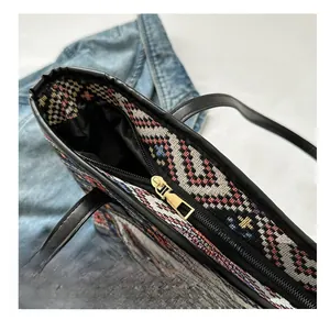Detail of ethnic woven tote bag featuring smooth metal zipper and black leather trim