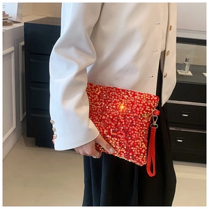 Detail of red sequin evening clutch bag featuring a shiny surface and golden metal hook