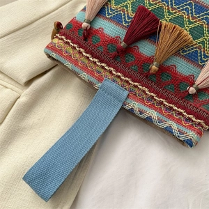 Dettaglio di borsa etnica ricamata con motivi a zigzag colorati e nappe decorative