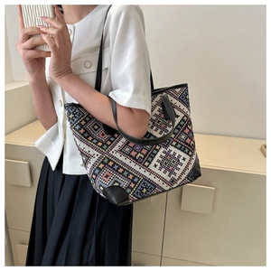 Detailed close-up of ethnic tote bag with colorful embroidery and black leather trim