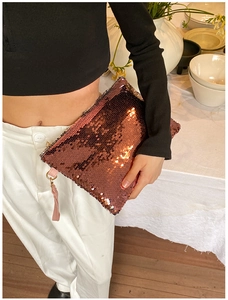 Detailed close-up of rose gold sequin clutch bag with pink wrist strap and zipper