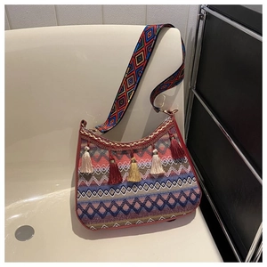 Detail of bohemian shoulder bag with ethnic weaving, tassel accents and geometric wide strap