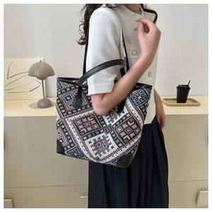 Close-up of geometric woven tote bag with premium black leather trim and handles