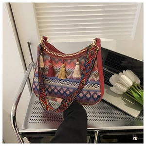 Detail of colorful woven bohemian hobo bag with red leather trim and fringe accents