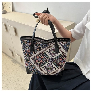 Detailed view of woven tote bag with colorful geometric patterns and black handle