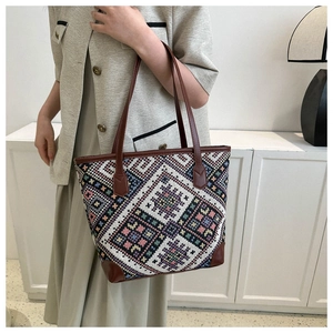 Detail of woven tote bag with geometric patterns, leather handles and reinforced corners