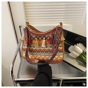 Detail of bohemian woven shoulder bag featuring colorful tassels and ethnic pattern strap