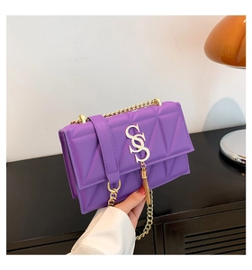 Close-up of purple quilted crossbody bag featuring a gold SS logo and tassel charm
