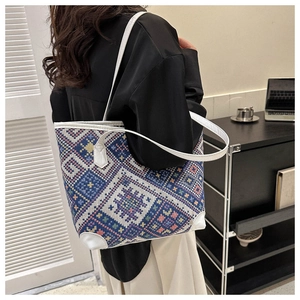 Detail of a large woven tote bag with geometric patterns worn by a model in soft lighting