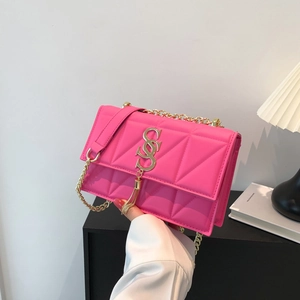 Detailed view of hot pink square bag featuring diamond quilting and gold S-buckle tassel