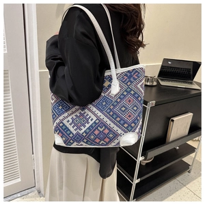 Close-up of ethnic woven tote bag with blue and pink geometric pattern and white leather straps