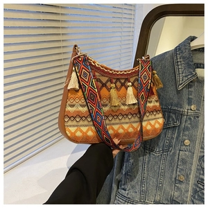 Close-up of ethnic woven shoulder bag with colorful tassels and geometric wide strap