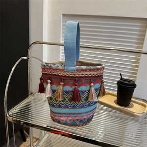 Dettaglio della borsa a secchiello boho intrecciata con frange colorate e motivi geometrici