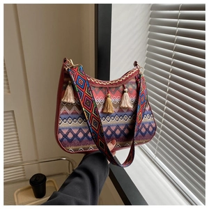 Detailed shot of ethnic woven bag with boho tassels and wide embroidered shoulder strap