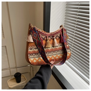 Detailed close-up of bohemian woven crossbody bag with colorful tassels and wide strap