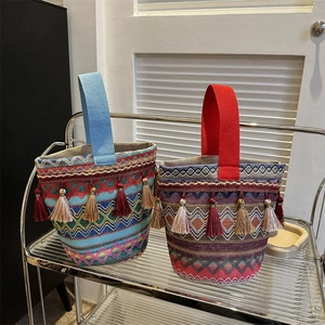 Dettaglio di borse a secchiello tessute in stile boho con nappe colorate su supporto in metallo