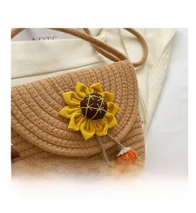 Dettaglio borsa a tracolla in paglia con girasole giallo e ciondoli a forma di frutta