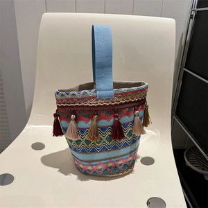 Dettaglio di borsa a secchiello etnica tessuta a mano con motivi colorati e nappine