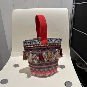 Dettaglio della borsa a secchiello boho intrecciata con nappe colorate e motivi geometrici