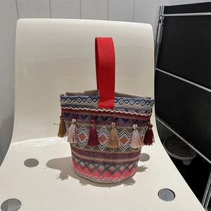 Dettaglio della borsa a secchiello boho intrecciata con righe colorate e nappe decorative