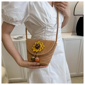 Dettaglio della mini borsa a tracolla in paglia con girasole giallo e pompon