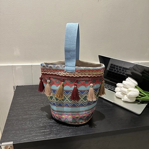 Dettaglio della borsa a secchiello etnica intrecciata con motivi colorati e nappe lunghe
