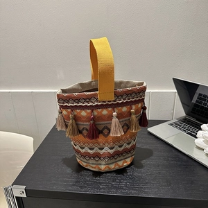 Dettaglio della borsa a secchiello bohémien con motivi intrecciati e vivaci frange